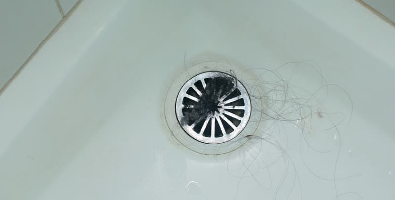 hair on top of the strainer of a shower drain
